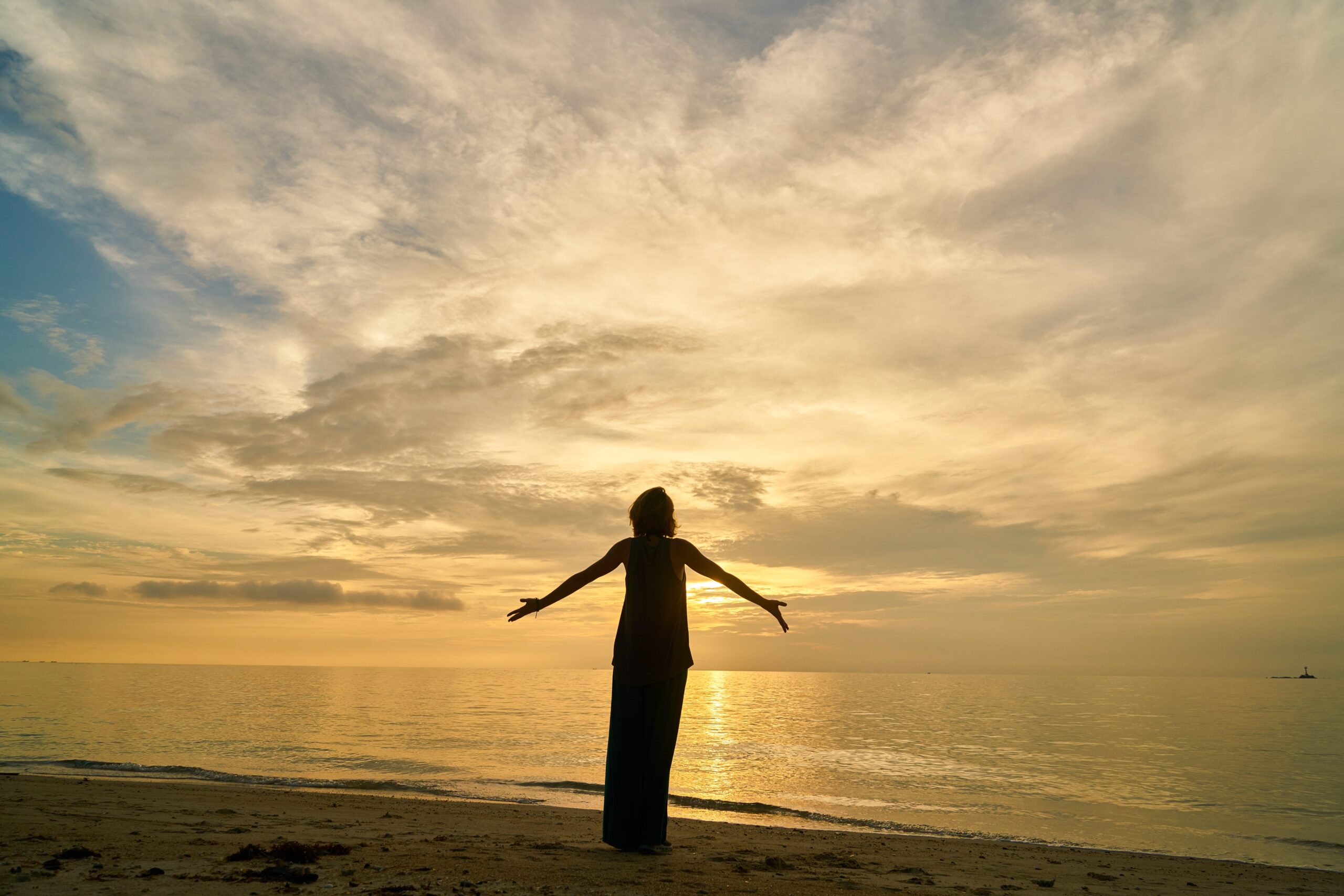 Person embracing the sunrise, symbolizing emotional healing and new beginnings.